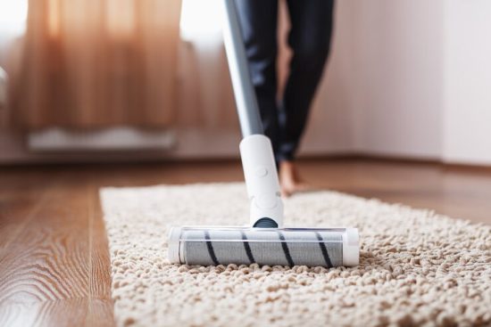 cordless-vacuum-cleaner-cleans-carpet-living-room-with-bottom-legs-modern-technologies-cleaning-house_94046-8292