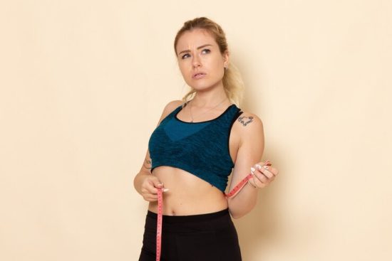 front-view-young-female-sport-outfit-measuring-her-sizes-waist_140725-85471